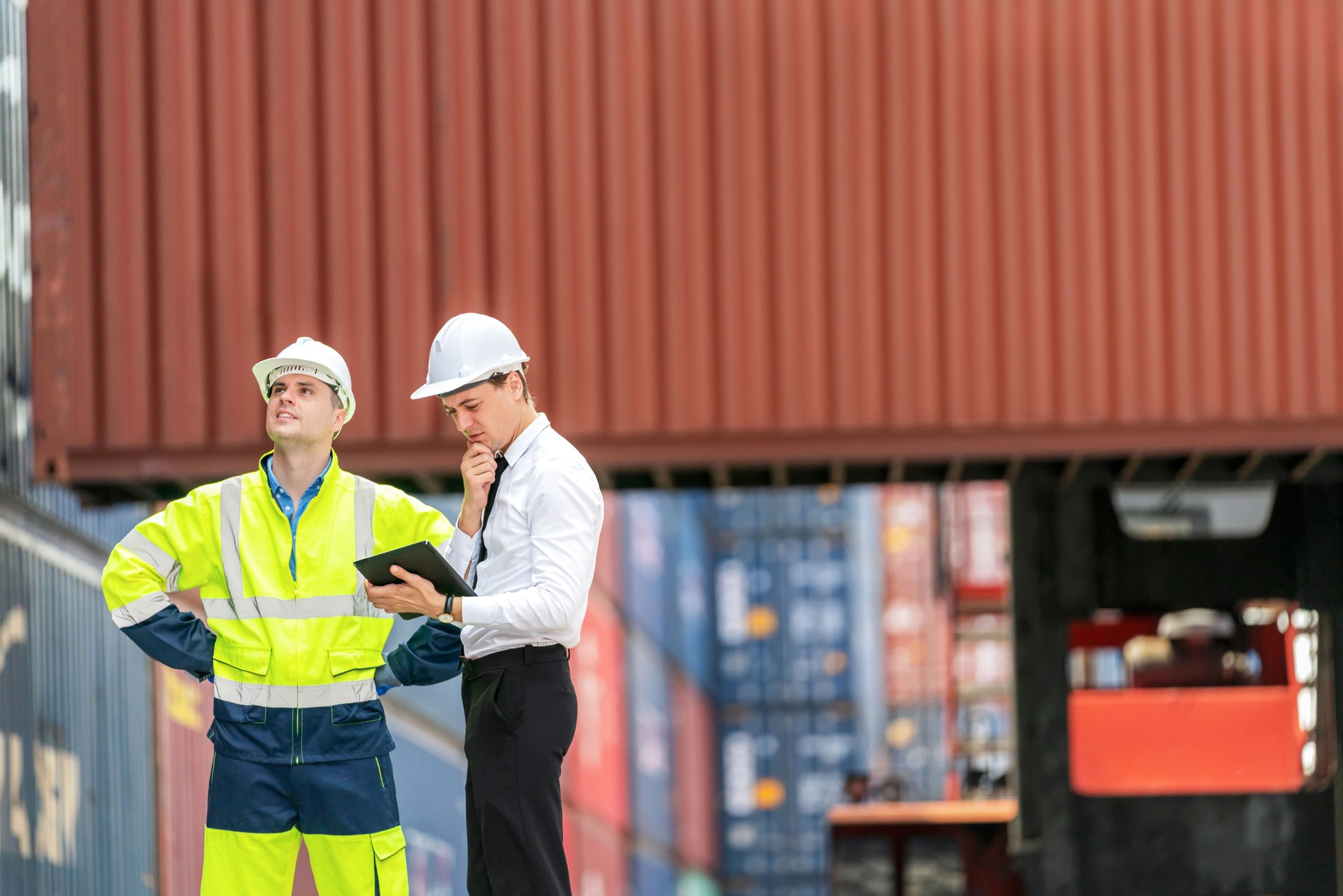 Dock manager and engineer worker looking at tablet in shipping yard during truck lifting cargo box. Import and export product. Manufacturing transportation and global business concept